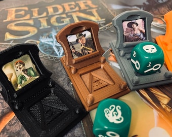 May include: Four 3D printed game pieces for the board game Elder Sign. Each piece features a small picture frame with a different character from the game. The pieces are brown, black, and gray. There are three green dice with white symbols on them.
