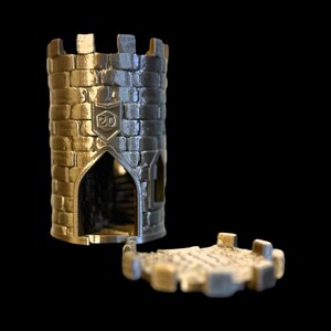 May include: A silver metal tower with a brick pattern and a small opening. The tower is a dice rolling tower with a removable lid. The lid is a flat piece of metal with a brick pattern. The tower has the number "20" on the side.