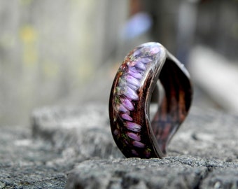 May include: A ring made of wood and resin with a band of purple flowers embedded in the resin.