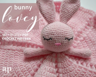 May include: A pink crocheted bunny lovey with black eyes and a pink nose. The bunny is attached to a pink crocheted blanket. The text "bunny lovey" is written in white on a pink background. The text "STEP BY STEP PDF CROCHET PATTERN" is written in black below the bunny. The text "ap THE ARTFUL PEA" is written in black at the bottom of the image.