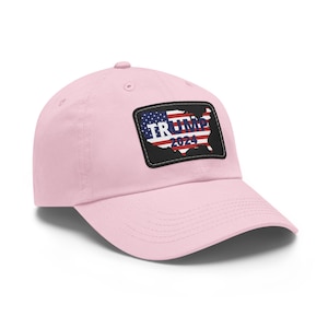 May include: A pink baseball cap with a black patch featuring a US map with an American flag design and the text "TRUMP 2024".