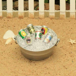 May include: A silver metal bucket filled with ice and six miniature cans of beer and soda. The cans are labeled "Beer" and "Cola".
