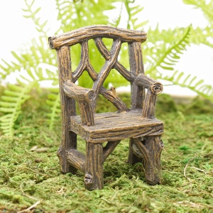 Puede incluir: Una silla de madera en miniatura con un diseño rústico de ramas. La silla es marrón y tiene una construcción simple y robusta.