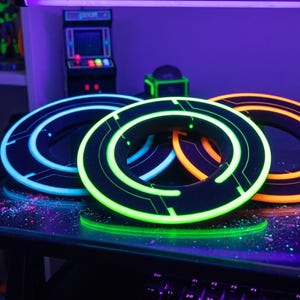 May include: Three glowing, circular objects with black and neon accents are displayed on a table. The objects have a futuristic design, with neon blue, green, and orange lights. The scene is illuminated by a purple light.