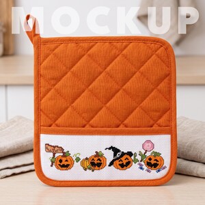 Può includere: Una presina quadrata trapuntata color arancione con una tasca in tela Aida bianca decorata con un motivo di Halloween a punto croce. Il ricamo raffigura quattro zucche, una delle quali indossa un cappello da strega, un cartello e un lecca-lecca rosa.