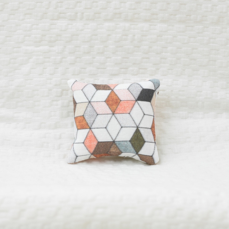 May include: A square pillow with a geometric pattern in shades of orange, brown, gray, and white.