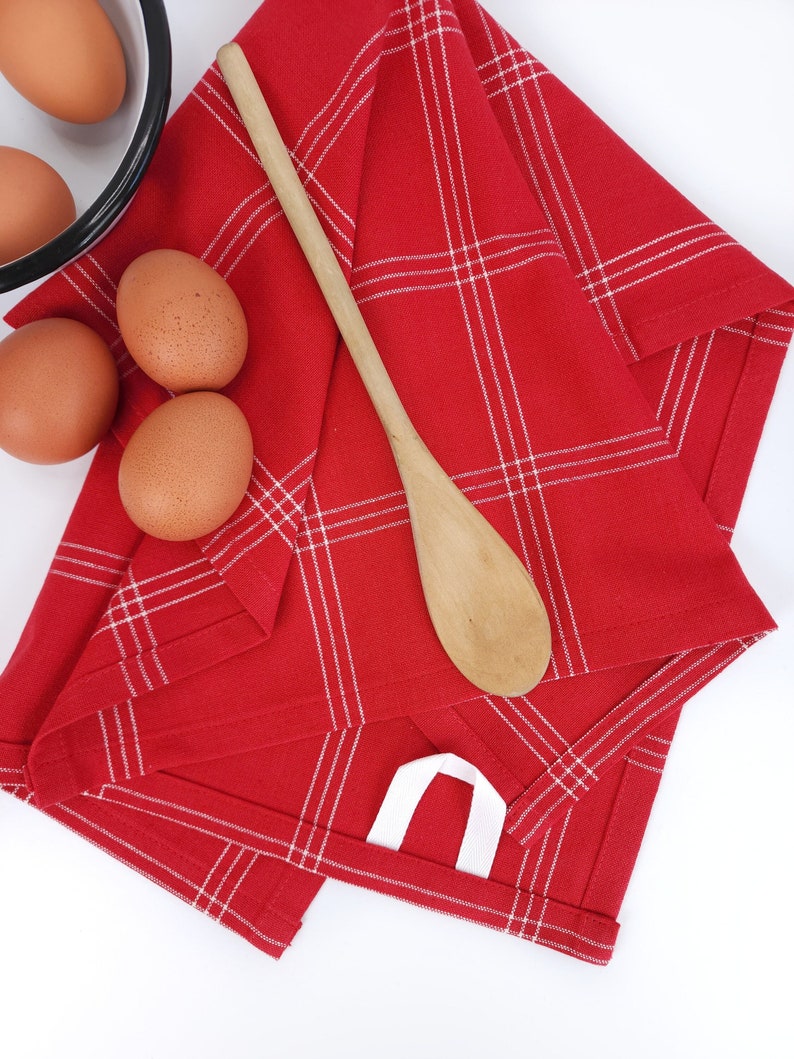 Ar ed plaid towel on a kitchen counter with a bowl, eggs, and a mixing spoon.