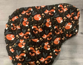 May include: A black fleece saddle pad with a repeating pattern of orange foxes and green leaves.