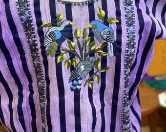 May include: A short-sleeved blouse featuring vertical stripes in shades of light purple and dark navy blue. The front is decorated with an embroidered design of three birds perched on green leafy branches, flanked by two vertical floral trim panels.