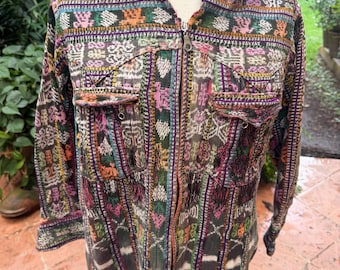May include: A long-sleeve zip-up jacket featuring a multi-colored woven pattern with vertical stripes and geometric shapes in shades of green, pink, orange, and purple. The jacket includes a pointed collar and two chest pockets with flaps.