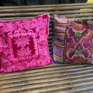 Puede incluir: Dos almohadas decorativas con motivos florales. La almohada de la izquierda es de terciopelo rosa brillante con bordados rosas. La almohada de la derecha es de tejido tejido multicolor con un motivo floral.