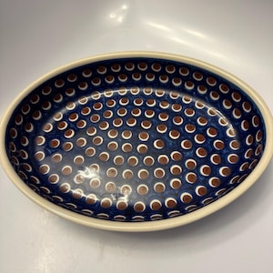 May include: A blue and brown oval ceramic baking dish with a polka dot pattern.