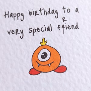 May include: A birthday card with the handwritten message "Happy birthday to a very special friend." The card features a cartoon orange monster with one eye, a yellow crown, and red feet.