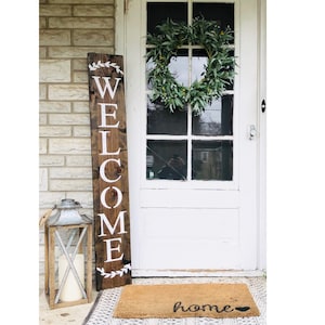 Rustic brown welcome sign with wreath accents at top and bottom