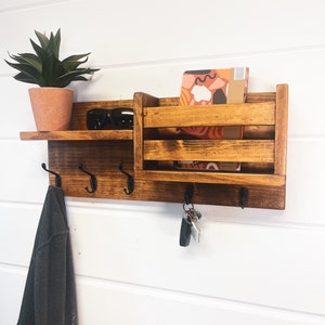 coat rack with hooks for keys, coats and hats. Features a shelf and a pocket for mail .