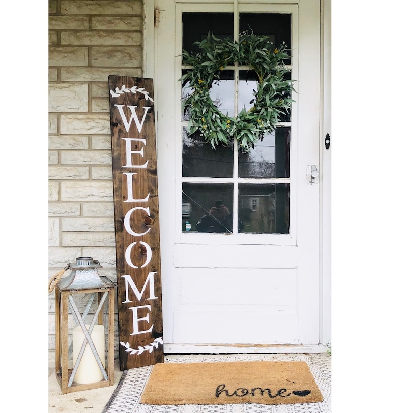 Rustic brown welcome sign with wreath accents at top and bottom