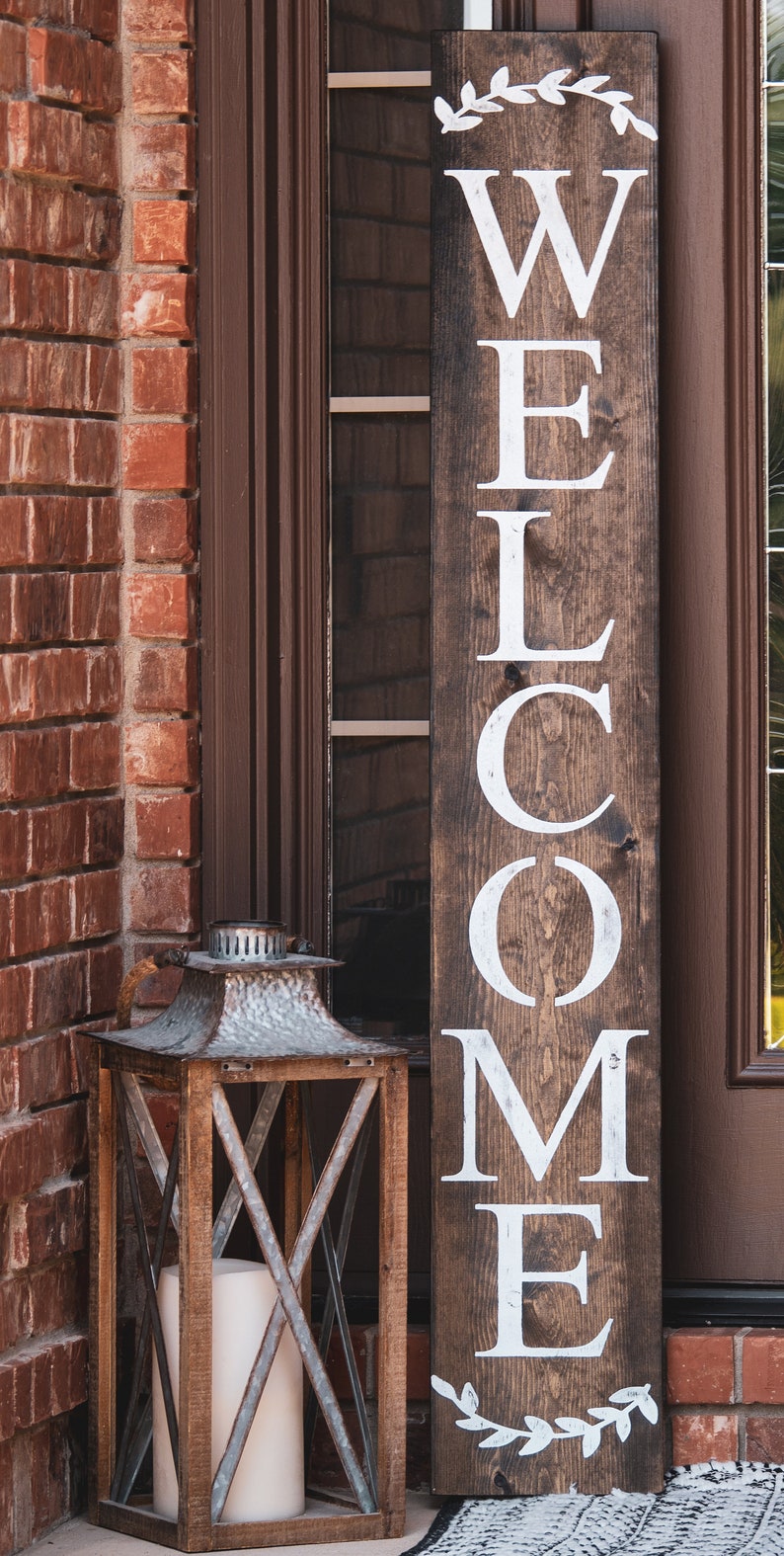 Welcome sign for front porch, brown in color, roman font with wreath accents at top and bottom