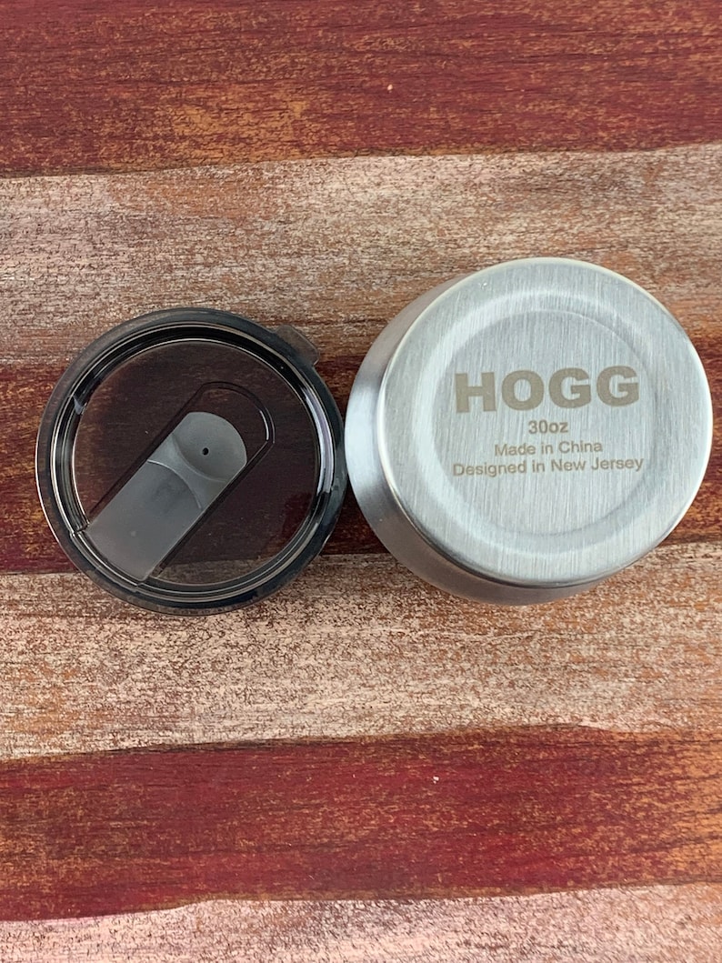 May include: A silver lid for a 30oz tumbler with the text "HOGG 30oz Made in China Designed in New Jersey" engraved on the top.