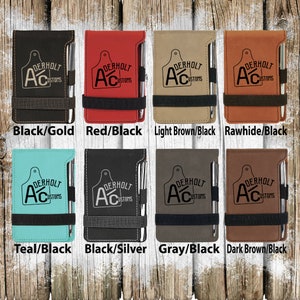 Puede incluir: Ocho combinaciones de colores diferentes de una libreta de cuero sint&eacute;tico con un bol&iacute;grafo adjunto. La libreta tiene un logotipo en blanco y negro que dice "Derholt Customs" con una "A" estilizada y un dise&ntilde;o de etiqueta de ganado. Los colores son negro/oro, rojo/negro, marr&oacute;n claro/negro, cuero crudo/negro, azul verdoso/negro, negro/plata, gris/negro y marr&oacute;n oscuro/negro.