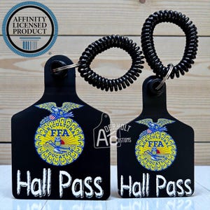 May include: Two black plastic livestock-style tags featuring the FFA emblem with an eagle, owl, and plow. Each tag has the text Hall Pass in white and is attached to a black coiled wristband. The emblem includes the words Agricultural Education.