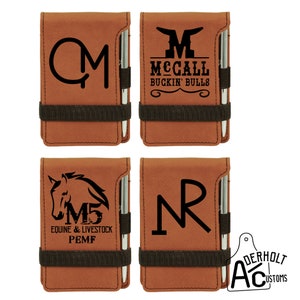 Puede incluir: Cuatro blocs de notas de imitaci&oacute;n de cuero marr&oacute;n con un portaplumas y una banda el&aacute;stica negra. Cada bloc de notas tiene un dise&ntilde;o diferente: un monograma "QM", un logotipo con el texto "McCall Buckin' Bulls", una cabeza de caballo con el texto "M5 Equine & Livestock PEMF", y un monograma "NR".