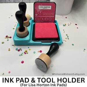 May include: A teal ink pad and tool holder with a dusky rose ink pad and three blending tools. The ink pad is labeled "Cloud 9 Dusky Rose" by Lisa Horton Crafts. The text "INK PAD & TOOL HOLDER" is at the bottom.