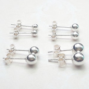 May include: Six pairs of silver ball stud earrings. Each earring has a small silver ball attached to a post with a butterfly back.