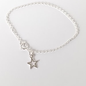 May include: A silver chain bracelet with a star charm. The chain is a delicate, cable style. The star charm is open and has a simple design.