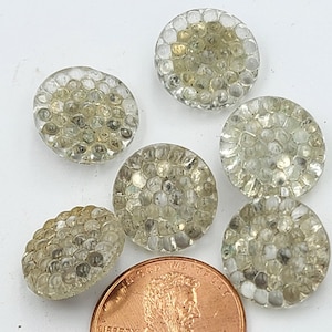 Puede incluir: Seis botones de vidrio transparente con una superficie texturizada. Los botones son aproximadamente del tamaño de una moneda de un céntimo de euro.