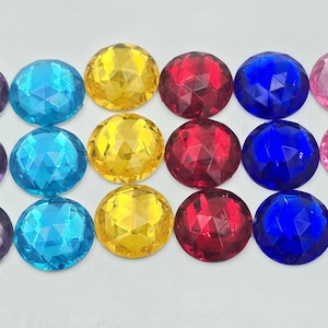 May include: Assortment of 18 round, faceted, plastic gems in six colours: purple, blue, yellow, red, pink, and light pink.