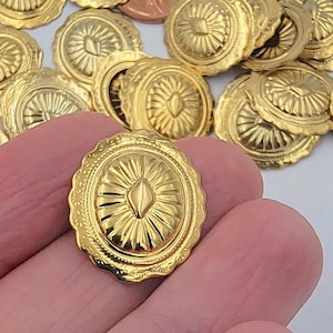 Puede incluir: Primer plano de un adorno de metal dorado con un diseño en forma de diamante en relieve en el centro. El adorno tiene un borde festoneado y una superficie texturizada.