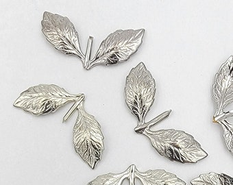 May include: Silver metal leaf embellishments, perfect for adding a touch of elegance to crafts and jewelry making. The leaves are approximately the size of a US penny.