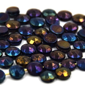May include: A pile of iridescent glass beads in shades of blue, purple, and brown. The beads are round and have a faceted surface.