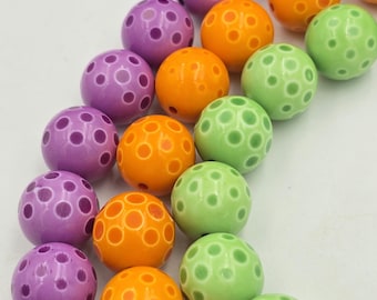 Puede incluir: Una hebra de cuentas de colores con una superficie texturizada. Las cuentas son moradas, naranjas y verdes.