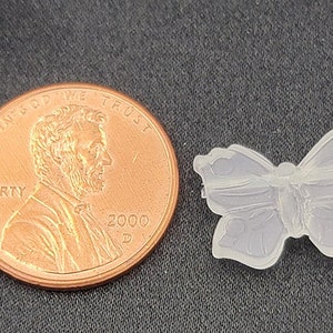 May include: A clear plastic butterfly charm, about the size of a UK penny. The butterfly has a detailed design with intricate wing patterns.