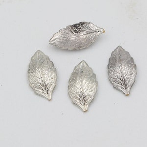 Puede incluir: Cuatro adornos de hojas de metal plateado con un diseño texturizado.