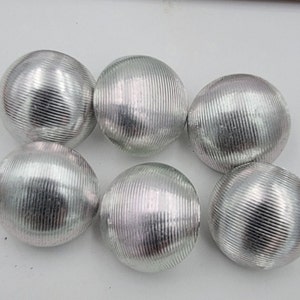 Puede incluir: Seis botones redondos de color plateado con textura acanalada.