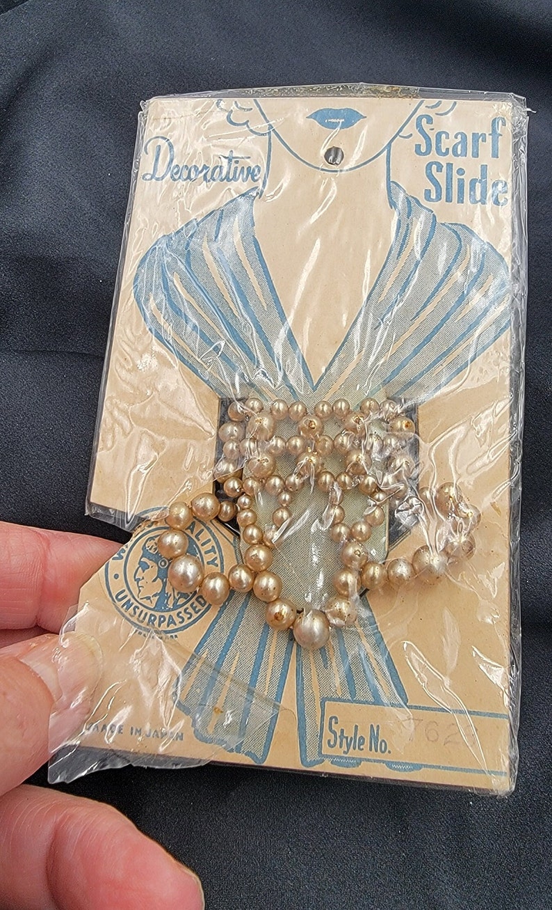 May include: A package containing a pearl necklace with a blue and white scarf printed with the text "Decorative Scarf Slide" and "Style No. 62". The package also has the text "Quality Unsurpassed" and "Made in Japan".