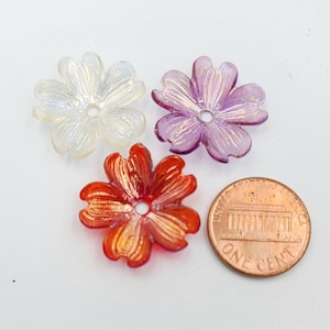 Può includere: Tre decorazioni di fiori in plastica iridescente in bianco, viola e rosso. I fiori sono circa delle dimensioni di una moneta da un centesimo di dollaro americano.