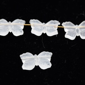 May include: Four clear glass butterfly beads. The beads are strung on a gold wire.
