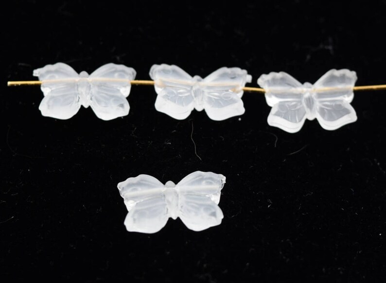 May include: Four clear glass butterfly beads. The beads are strung on a gold wire.
