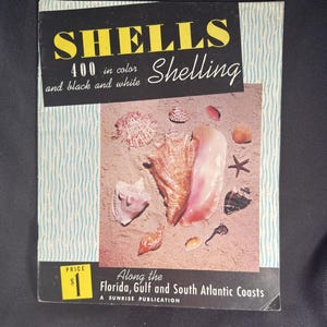 May include: Vintage book cover titled "SHELLS" with the text "400 in color and black and white." The cover features a collection of seashells on a sandy background. The text "Shelling" is also present. The price is $1.