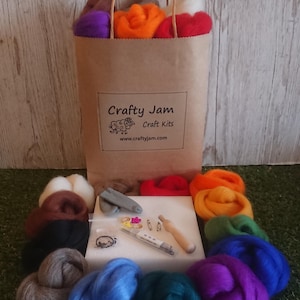 May include: A brown paper bag with the text "Crafty Jam Craft Kits" and the website address "www.craftyjam.com". The bag is filled with colourful wool roving, felting needles, a felting tool, and other supplies for needle felting.