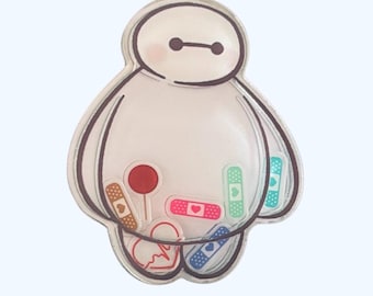 May include: A clear plastic pin featuring a cartoon character resembling Baymax from the Disney movie Big Hero 6. The character is filled with colorful bandaids and a red lollipop.
