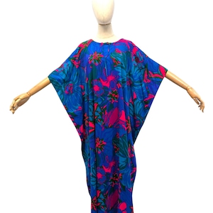 May include: A blue caftan dress with a vibrant floral pattern in shades of pink and teal. The dress has a loose, flowing silhouette and wide sleeves. The fabric appears lightweight, suitable for warm weather.