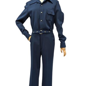 Puede incluir: Un mono azul marino con camisa de cuello, mangas largas y cintur&oacute;n con detalles met&aacute;licos.