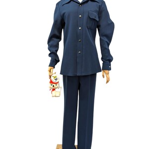 Puede incluir: Una camisa azul marino de manga larga con cuello abotonado y un solo bolsillo en el pecho izquierdo. La camisa se combina con pantalones azul marino a juego.