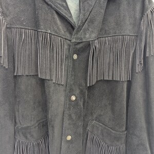May include: Black suede jacket with fringe detailing across the chest, pockets, and sleeves. The jacket has a button-up front and a collar. The brand name "Schott" is visible on the label.