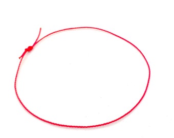 May include: A red string bracelet with a simple knot closure.