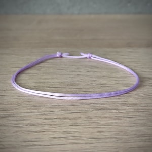 Puede incluir: Un sencillo brazalete de cordón de color lila con cierre de doble nudo.